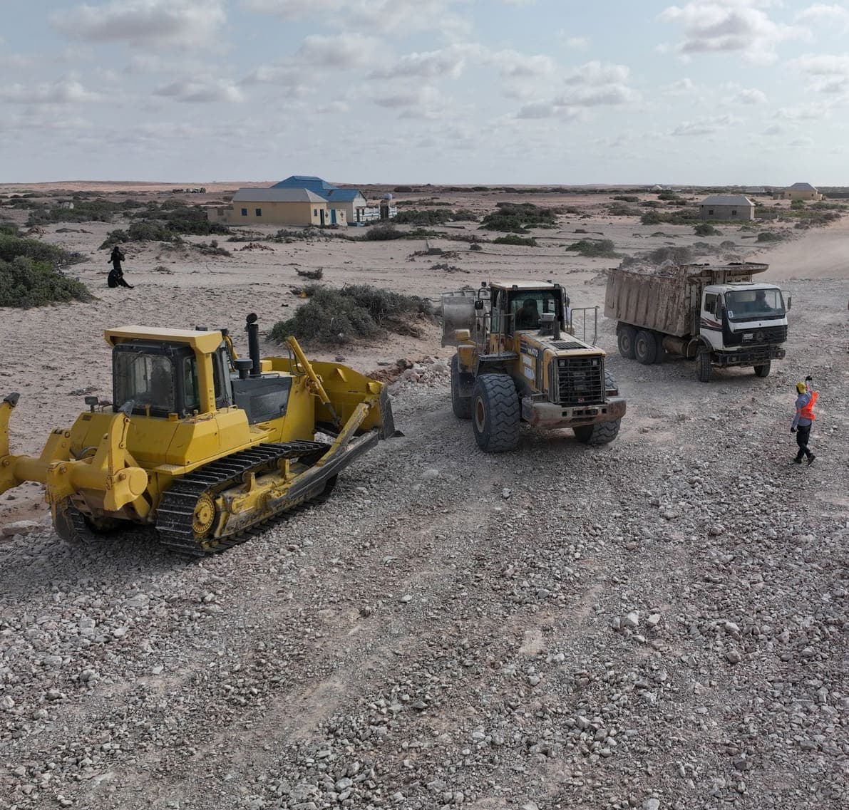 Bulldozer, wheel loader and tipper truck preparing a gravel road bed